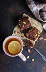 Tea with lemon and mint leaf with homemade biscuit brownie with pistachios for Breakfast on wooden tray on stone table background. Close-up, top view. copy space