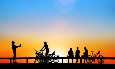 Fototapeta na wymiar Silhouette group friend and bike relaxing with sunrise background.