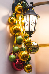 Fototapeta na wymiar Street lantern decorated for Christmas with beautiful red, green and golden glass handmade balls. Flickering in night