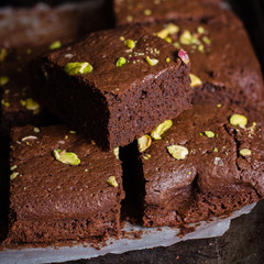 Homemade chocolate brownies with pistachios on dark background. Copy space