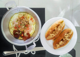 Fried eggs in a frying pan with bread for breakfast on the table.