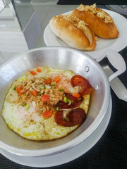 Fried eggs in a frying pan with bread for breakfast on the table.