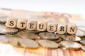 Steuern / Geld und Holzwürfel mit dem Wort Steuern