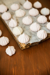 Fototapeta na wymiar lots of little meringues on dark wooden background