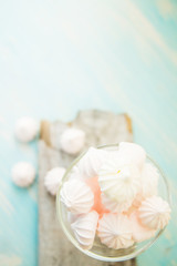 Some delicious pink macarons in a glass jar on a white wooden table with a robin egg blue background. Vintage Style.