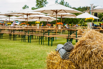 Picnic area with tables and umbrellas, bales of hay in the foreground