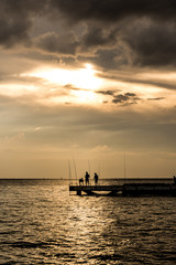 Fototapeta na wymiar Fisherman silhouette with sunset sky at the sea
