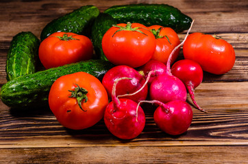 Ripe tomatoes, radish and cucumbers on wooden table