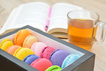 Colorful macaroons for breakfast - on a background of a book with a pencil.