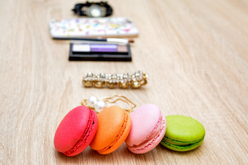 Pasta macaroons, women's bracelet, cosmetics, jewelry, mascara, watches, phone. Woman's glamour beauty tools.