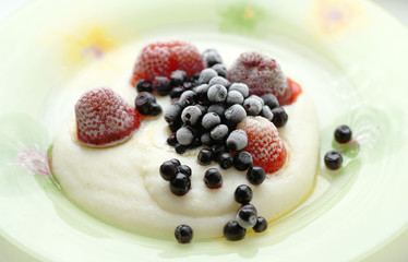 Manna porridge with frozen berries close-up. Food for children with blueberries and strawberries for breakfast.