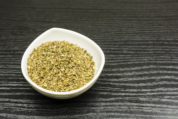 Dried basil in a white bowl.