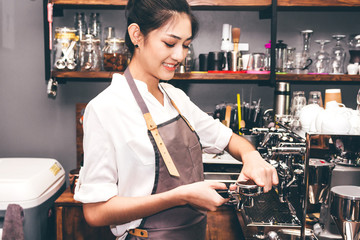 Women Barista using coffee machine for making coffee in the cafe