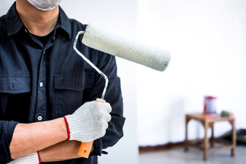 Male Painter with arm crossed holding paint roller, Interior working with paint roller in room,...