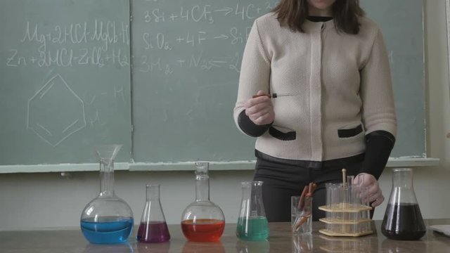 Young laborant, student dripping color liquid into a test tube and mixing chemicals in flask. Chemistry lab in university, college, school.
