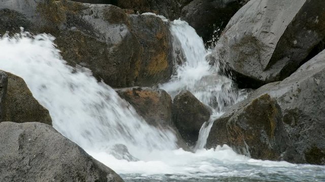 strong flows of river is draining from stones, close up