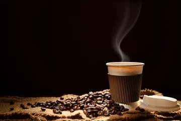 Rolgordijnen Paper cup of coffee with smoke and coffee beans on black background © amenic181