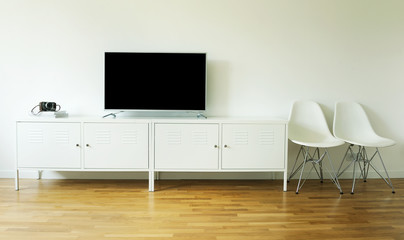 wide screen TV on white stand near light wall