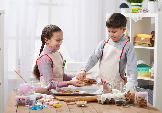 Boy and girl shows a baked cookies, home kitchen interior, homemade food concept