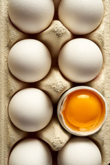Chicken eggs with white shells in a carton container, top view, close-up 