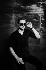 Studio portrait of stylish man wear on black shirt and glasses against steel wall.