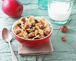 Corn flakes with hazelnuts and chocolate  in red bowl for breakfast on old cyan wooden table