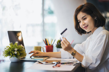 Young woman holding credit card and using laptop computer. Online shopping concept