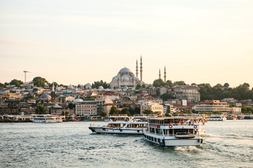 Boats sail along the Bosphorus on the background of beautiful views of Sambul at sunset.