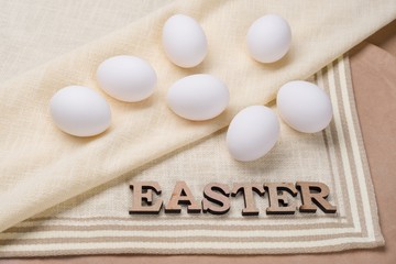 White eggs for dyeing and the word Easter on natural linen tablecloths