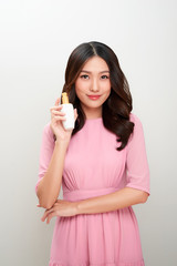 Smiling young asian woman showing skincare product.
