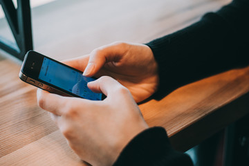 Close-up image of male hands using smartphone at night on city shopping street, searching or social networks concept