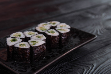 Flower from rolls maki sushi on a black stone plate. Fresh made Sushi set with cheese and cucumber. Traditional Japanese cuisine.