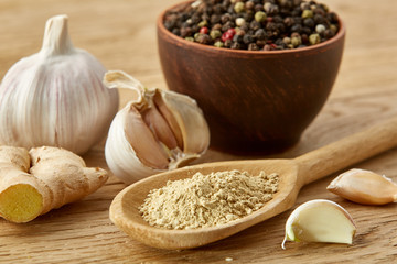 Composition of powder spices on spoon and different sorts of spicies on wooden table background, selective focus