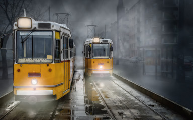 Two yellow streetcars (trams) at the terminus on a damp foggy day