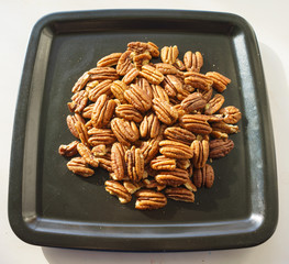 A bunch of nuts pecan on a black plate. Close-up photo 