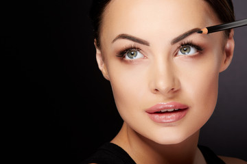 Woman painting eyebrows with black pencil