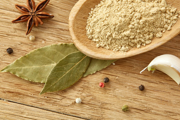 Composition of powder spices on spoon and different sorts of spicies on wooden table background, selective focus