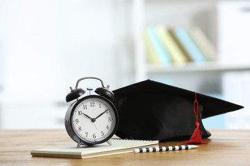 Alarm clock and graduation cap on table. Study goals