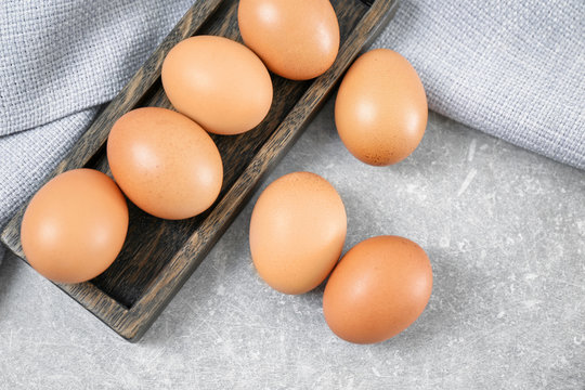 Wooden dish with chicken eggs on table