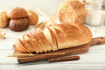 Wooden board with sliced bread on table