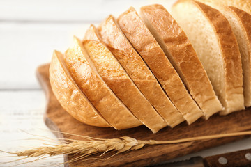 Wooden board with sliced bread on table