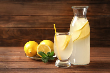Tasty lemonade with ice in glassware on table