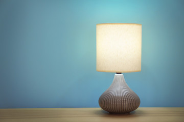Stylish lamp on table against color wall