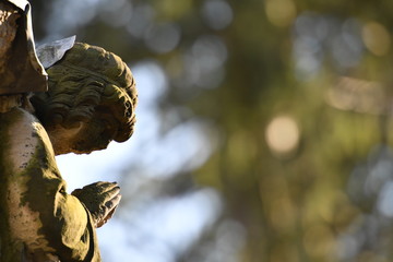 Weathered sculpture of a praying angel on a tomb 