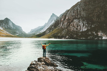 Traveler Man raised hands standing alone at sea stone Travel lifestyle survival emotional concept adventure outdoor active vacations wild scandinavian nature