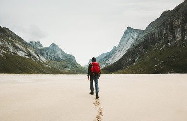 Man with red backpack walking alone at Horseid beach in Norway Travel lifestyle concept adventure...