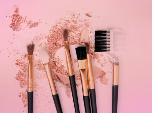 Brush make up set crushed make up power on pink background.