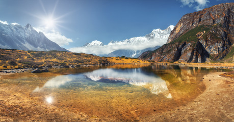 Beautiful scene with high rocks with snow covered peaks, mountain lake, reflection in water, blue...