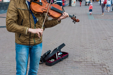 Street violinist plays the violin at noon, autumn day
