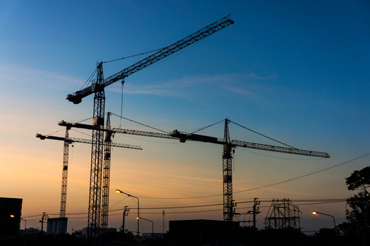 Silhouette of group of tower cranes in workplace. Building construction industrial in Thailand, Southeast Asia.